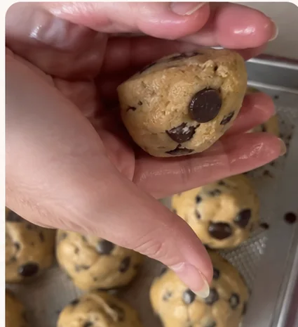 Foto caseira de celular de mãos boleando a massa de cookie